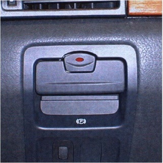Az elektromechanikus rögzítő fék kapcsolója a műszerfal bal oldalán gyermek biztonsági nyomógombbal is ellátva (Renault).